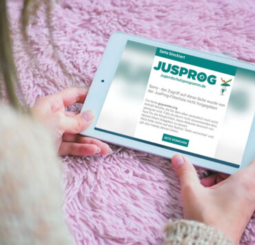 Frau bekommt auf Tablet Jugendschutz Hinweis eingeblendet